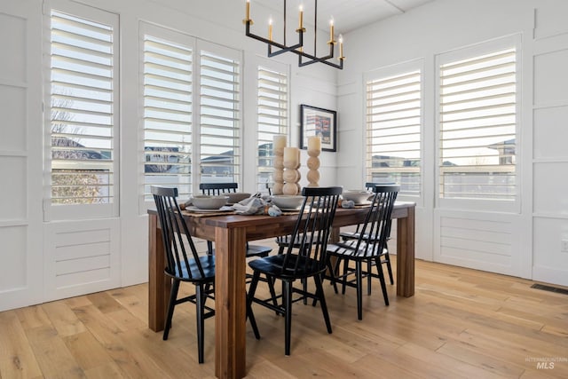 dining space with visible vents, light wood-style flooring, and an inviting chandelier