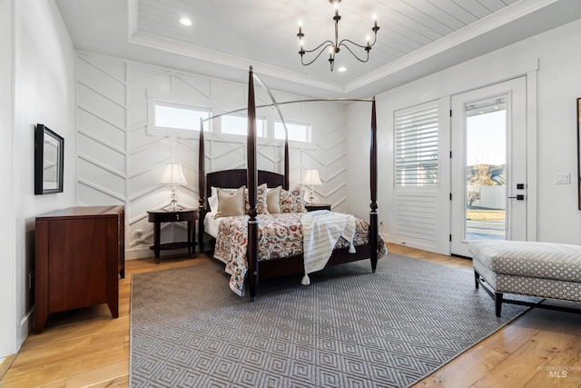 bedroom with a tray ceiling, access to exterior, and light wood-type flooring