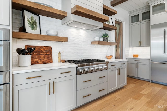 kitchen featuring gray cabinetry, open shelves, tasteful backsplash, stainless steel appliances, and custom exhaust hood