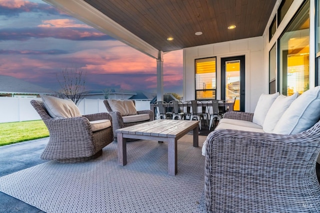 patio terrace at dusk with an outdoor living space and fence