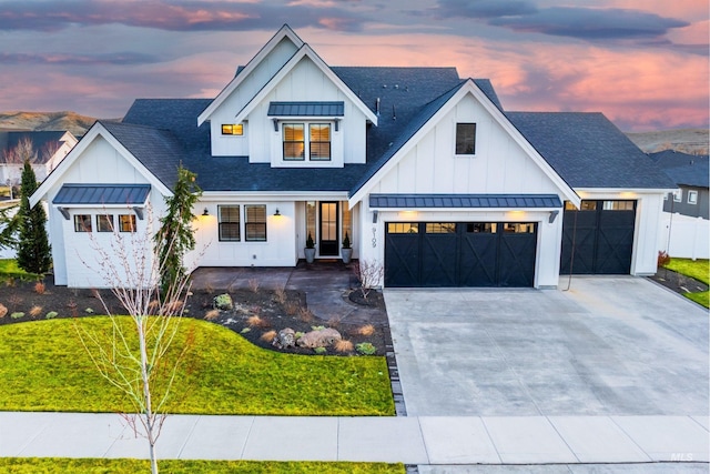 modern farmhouse featuring driveway, a standing seam roof, board and batten siding, a shingled roof, and metal roof