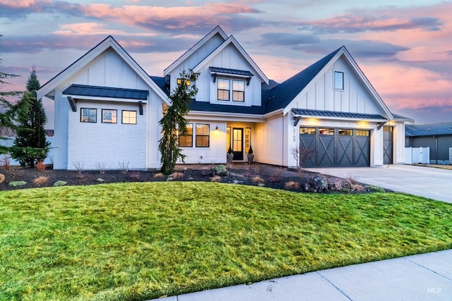 modern farmhouse style home with a standing seam roof, a front yard, board and batten siding, and driveway