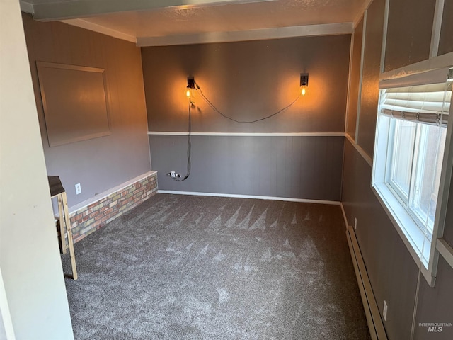 spare room with carpet floors, a baseboard heating unit, and wooden walls