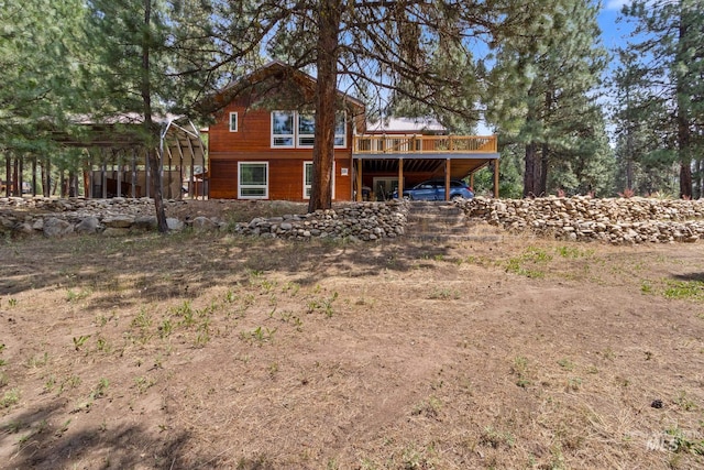 back of property with driveway, a deck, and a carport