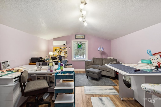 interior space with lofted ceiling, a textured ceiling, wood finished floors, and a wall mounted AC