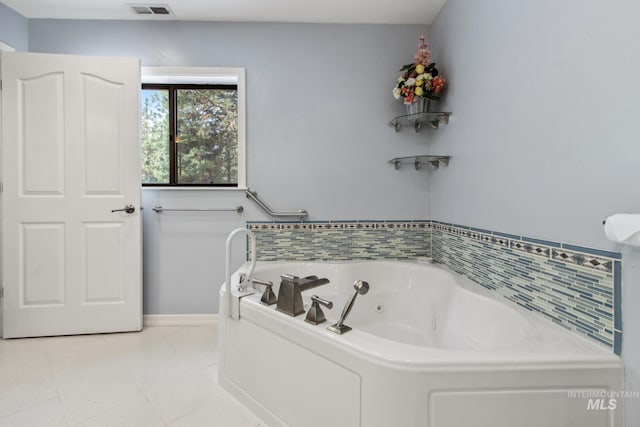 bathroom featuring baseboards, a tub with jets, visible vents, and tile patterned floors