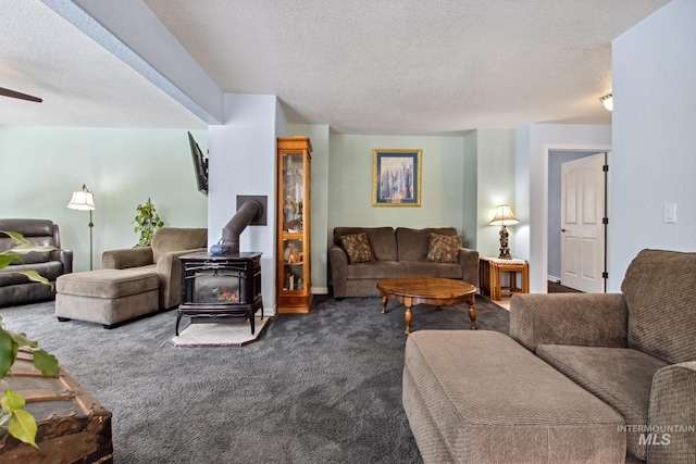 living area featuring a wood stove, a ceiling fan, dark carpet, and a textured ceiling