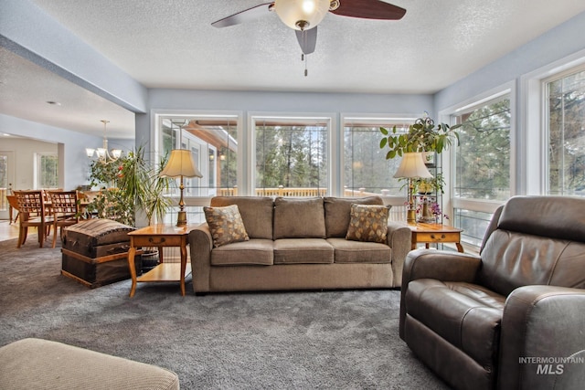 living room featuring carpet flooring, a textured ceiling, and ceiling fan with notable chandelier