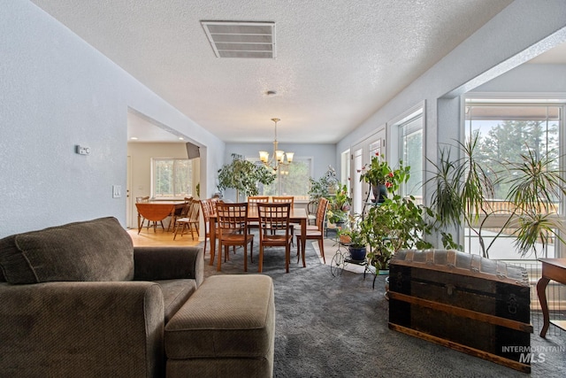 carpeted dining area featuring a notable chandelier, a textured ceiling, visible vents, and a healthy amount of sunlight