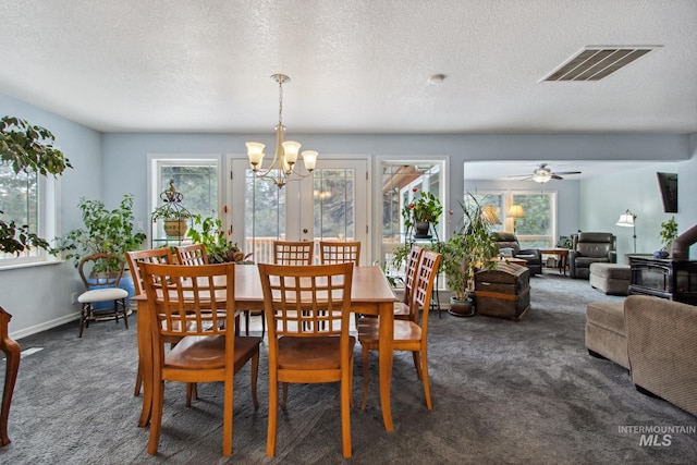 dining area featuring dark colored carpet, visible vents, an inviting chandelier, a wood stove, and baseboards