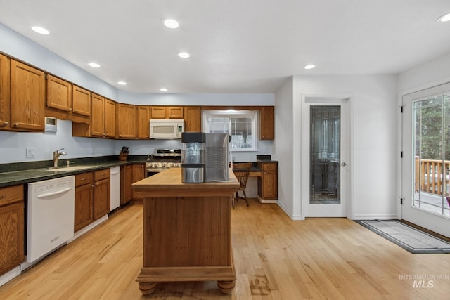 kitchen with recessed lighting, brown cabinetry, a sink, light wood-type flooring, and white appliances