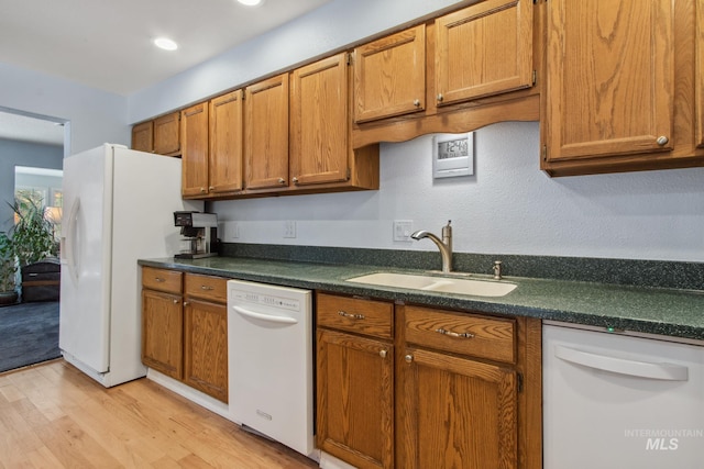 kitchen with dark countertops, white appliances, brown cabinets, and a sink