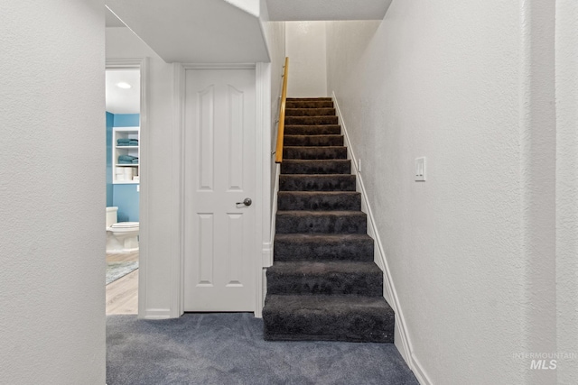 stairway with carpet floors and a textured wall