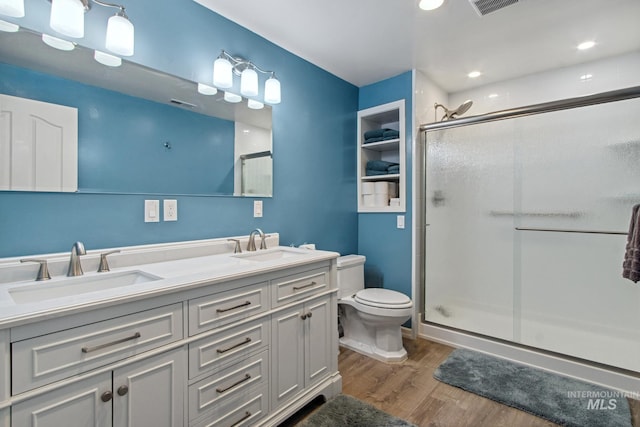 full bathroom with a sink, a shower stall, toilet, and wood finished floors