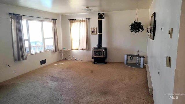 empty room featuring a wood stove and carpet floors