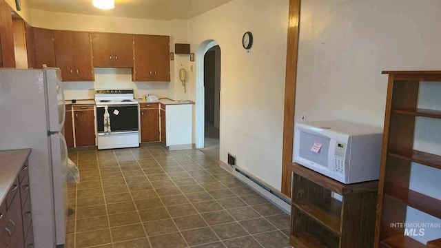 kitchen with white appliances, dark tile patterned floors, and a baseboard radiator