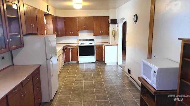 1120 N State St, Grangeville, ID 83530 - kitchen featuring white appliances, light countertops, brown cabinets, arched walkways, and dark tile patterned floors