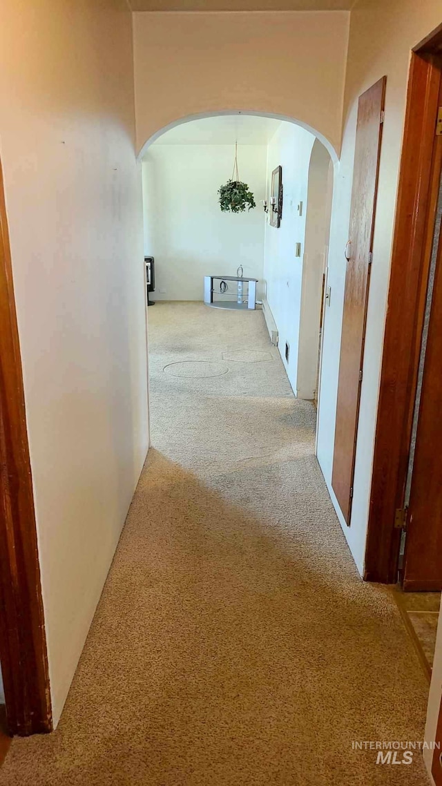 corridor with light carpet and an inviting chandelier