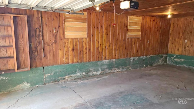 garage featuring a garage door opener and wooden walls