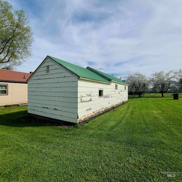 view of property exterior featuring a storage unit and a lawn