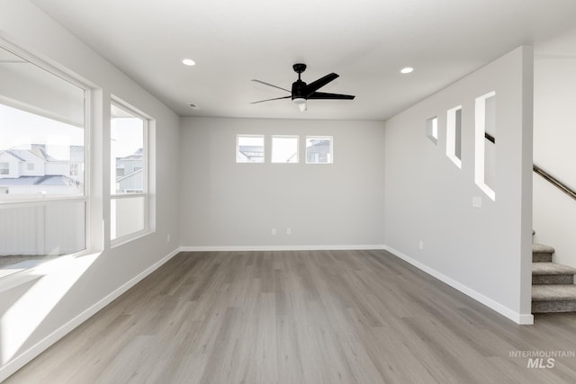 unfurnished room featuring recessed lighting, wood finished floors, ceiling fan, and stairs