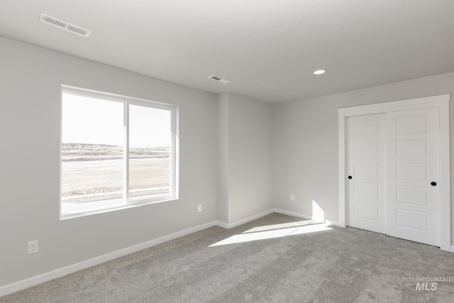 unfurnished room with carpet flooring, visible vents, baseboards, and recessed lighting