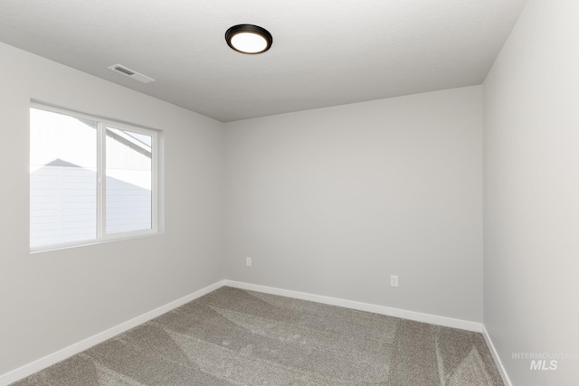 empty room featuring carpet, visible vents, and baseboards