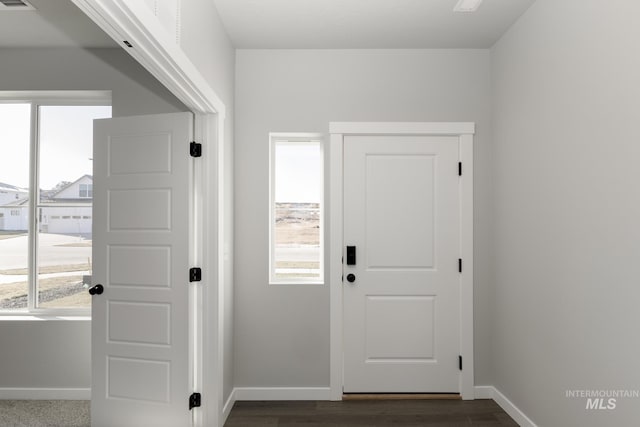 doorway to outside featuring baseboards, dark wood-style floors, and plenty of natural light