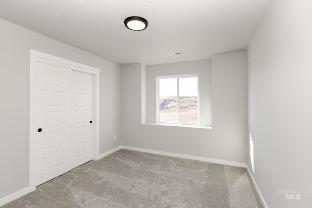unfurnished bedroom with baseboards, carpet flooring, a closet, and visible vents