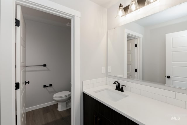 bathroom featuring toilet, baseboards, vanity, and wood finished floors