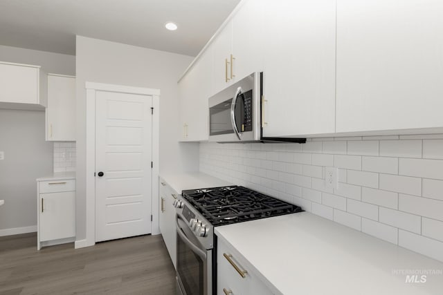 kitchen with light wood-style flooring, stainless steel appliances, white cabinetry, backsplash, and light countertops