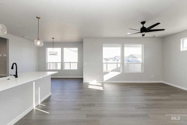 unfurnished living room featuring baseboards, a healthy amount of sunlight, and a sink