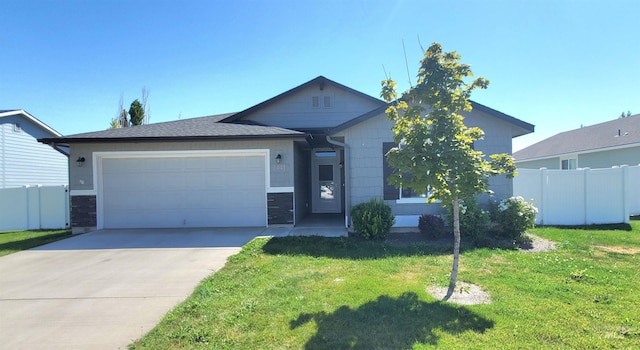 view of front facade with an attached garage, concrete driveway, a front lawn, and fence