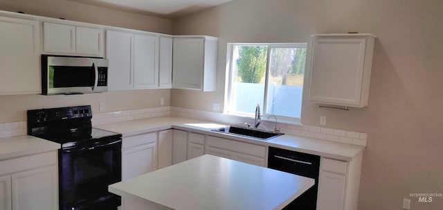 kitchen with a sink, black appliances, and white cabinets