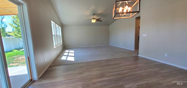 unfurnished room featuring ceiling fan with notable chandelier, lofted ceiling, and hardwood / wood-style floors