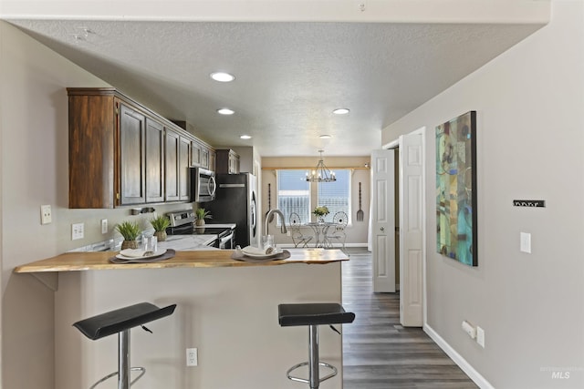 2908 E Iowa Ave, Nampa, ID 83686 - kitchen featuring appliances with stainless steel finishes, a breakfast bar area, a peninsula, dark wood-type flooring, and light countertops