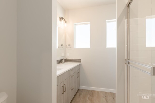 2804 N Eagle Meadow Ave, Kuna, ID 83634 - full bathroom with tasteful backsplash, baseboards, double vanity, wood finished floors, and a sink