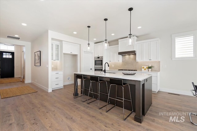 819 Cedar Point Way, Nampa, ID 83686 - kitchen with backsplash, a kitchen breakfast bar, white cabinetry, a center island with sink, and baseboards