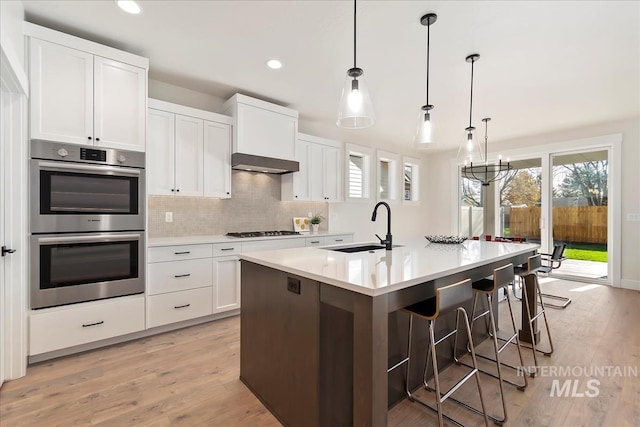 819 Cedar Point Way, Nampa, ID 83686 - kitchen with a sink, stainless steel double oven, gas cooktop, decorative backsplash, and light wood finished floors