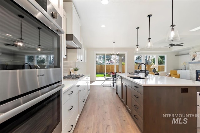 819 Cedar Point Way, Nampa, ID 83686 - kitchen with a sink, a stone fireplace, stainless steel appliances, light countertops, and white cabinetry