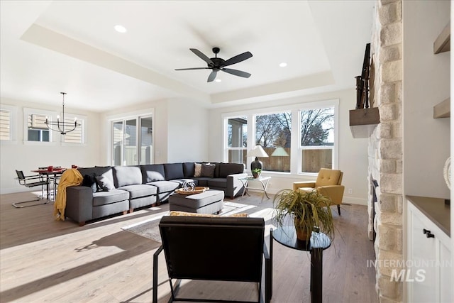 819 Cedar Point Way, Nampa, ID 83686 - living room with a tray ceiling, hardwood / wood-style floors, a ceiling fan, a chandelier, and a stone fireplace