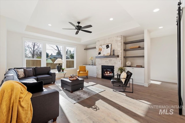 819 Cedar Point Way, Nampa, ID 83686 - living area with a tray ceiling, a stone fireplace, ceiling fan, wood finished floors, and recessed lighting