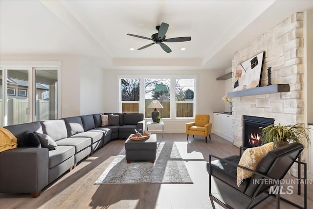 819 Cedar Point Way, Nampa, ID 83686 - living room with ceiling fan, a stone fireplace, wood finished floors, and a tray ceiling