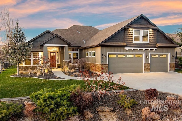 craftsman house featuring board and batten siding, concrete driveway, a lawn, stone siding, and an attached garage