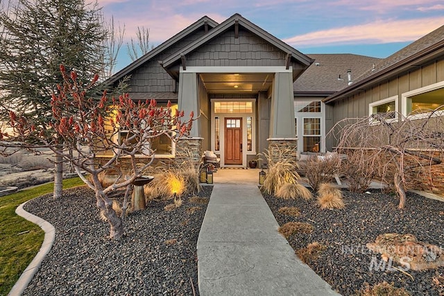 exterior entry at dusk featuring roof with shingles