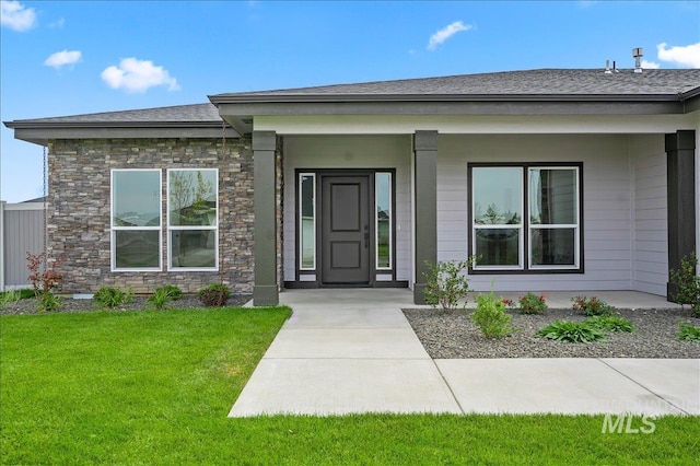 view of exterior entry with a porch and a yard