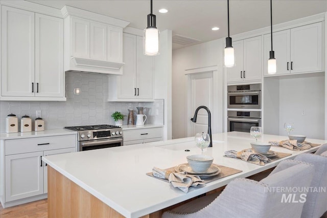 kitchen with white cabinets, an island with sink, and appliances with stainless steel finishes