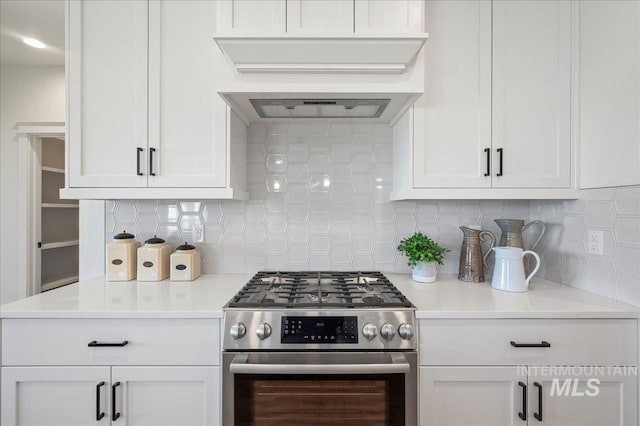 kitchen with white cabinets, backsplash, custom range hood, and stainless steel gas range oven