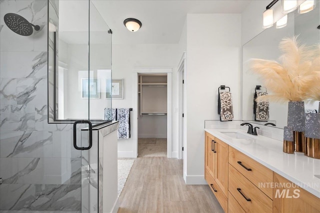 bathroom featuring walk in shower, vanity, and wood-type flooring