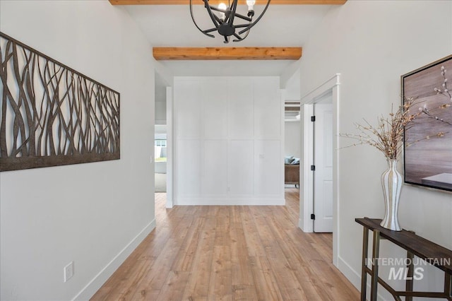 corridor featuring beam ceiling, light hardwood / wood-style flooring, and a chandelier